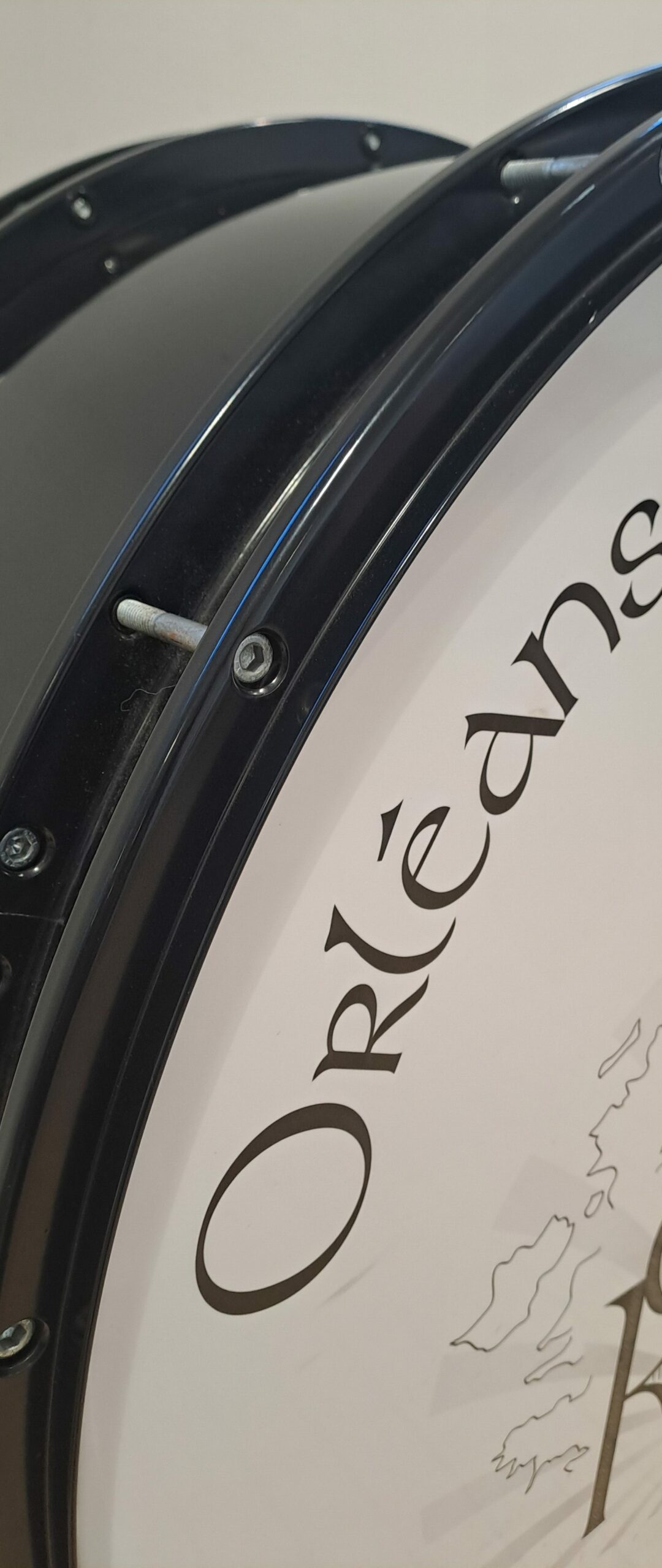 Gros plan d'un détail de la grosse caisse. Une partie de la peau, avec "Orléans" écrit dessus est visible, ainsi qu'une partie du corps de caisse